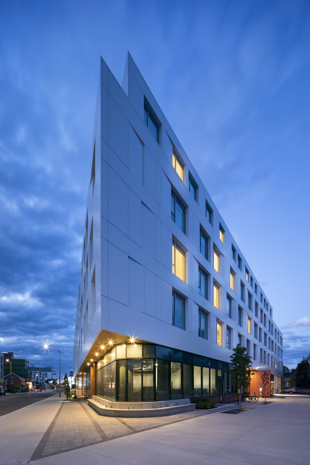 GEOpark white apartment building corner at blue hour with illuminated ground-floor entrance.