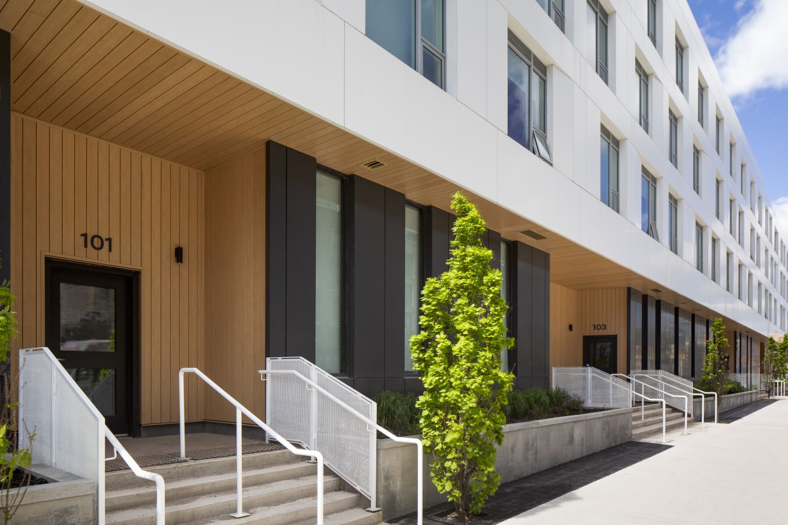 GEOpark exterior entrance with wood paneling, steps, ramps, and apartment doors numbered 101 and 103.
